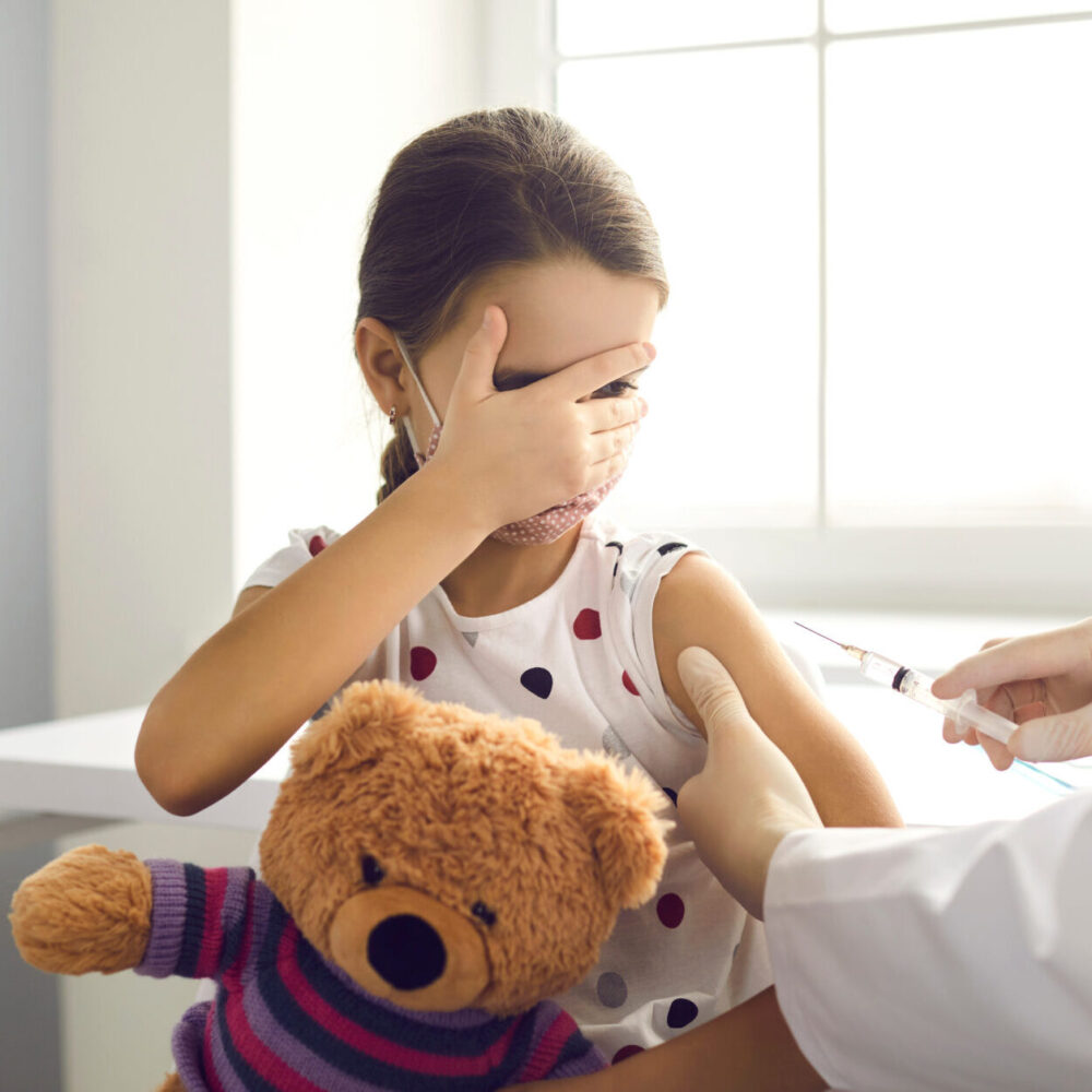 female child afraid of vaccine needle from health professional
