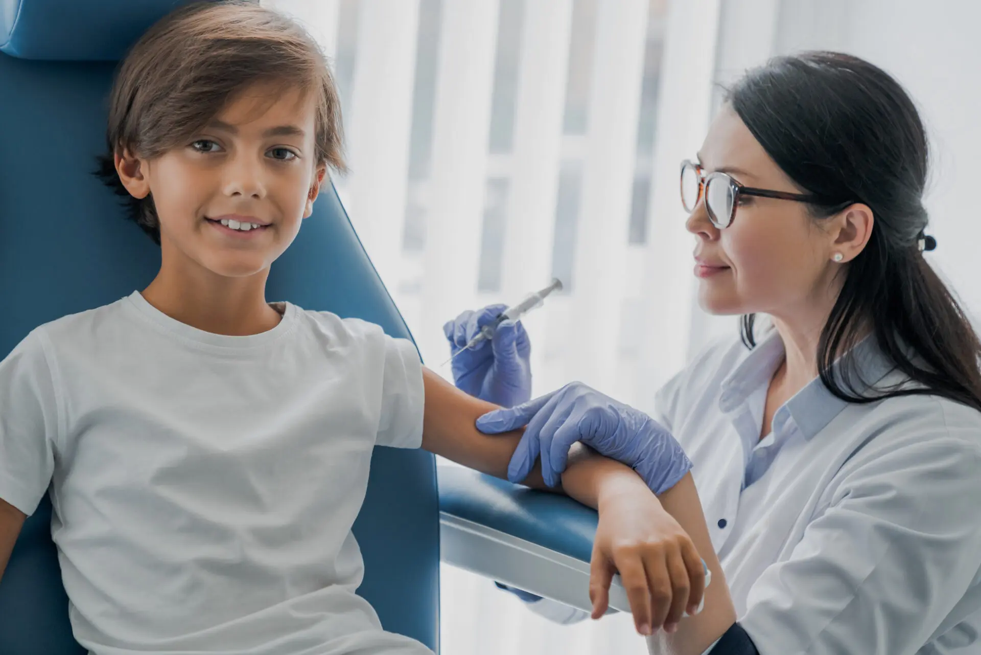 Female doctor pediatrician injecting vaccine to little boy in medical clinic Older child getting a vaccine