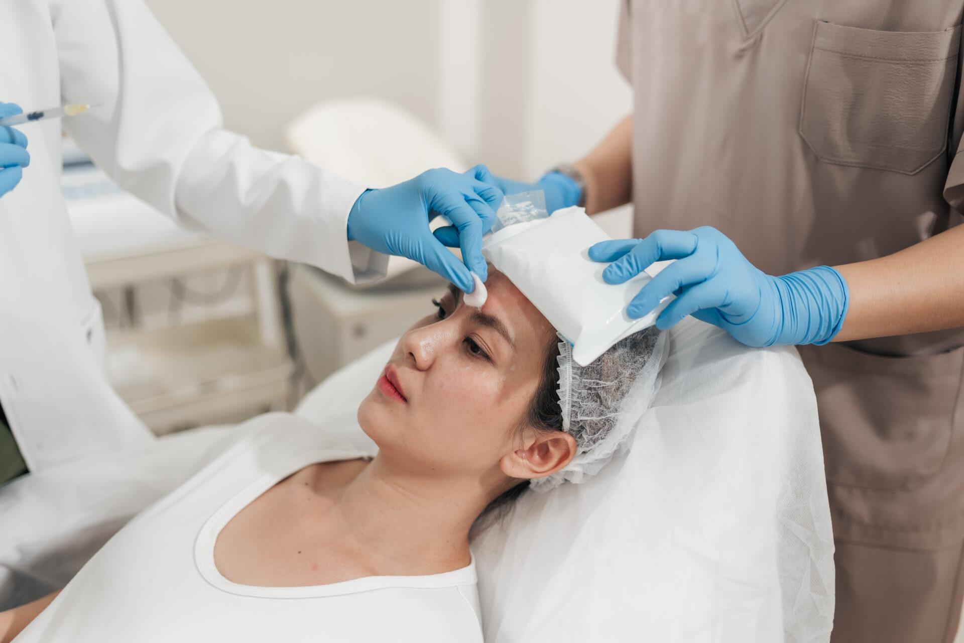 Asian woman receiving Assistant apply cold compresses to her face. Facial beauty injection procedure, A professional anti-aging beauty treatment in aesthetic clinic. cold compress after cosmetic procedure
