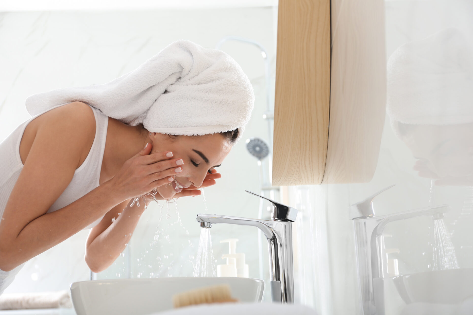 Happy young woman washing face in bathroom Woman washing face